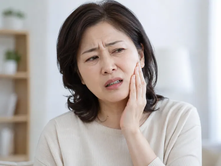 A woman holding her cheek in pain