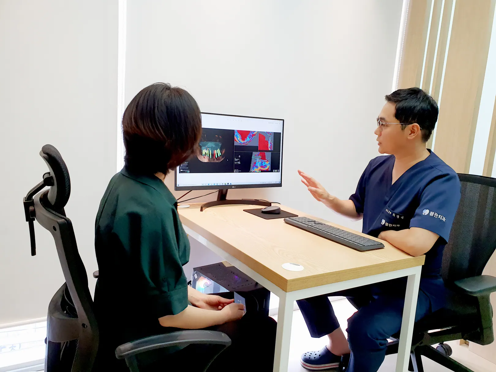 A dentist consulting with a patient while looking at a monitor